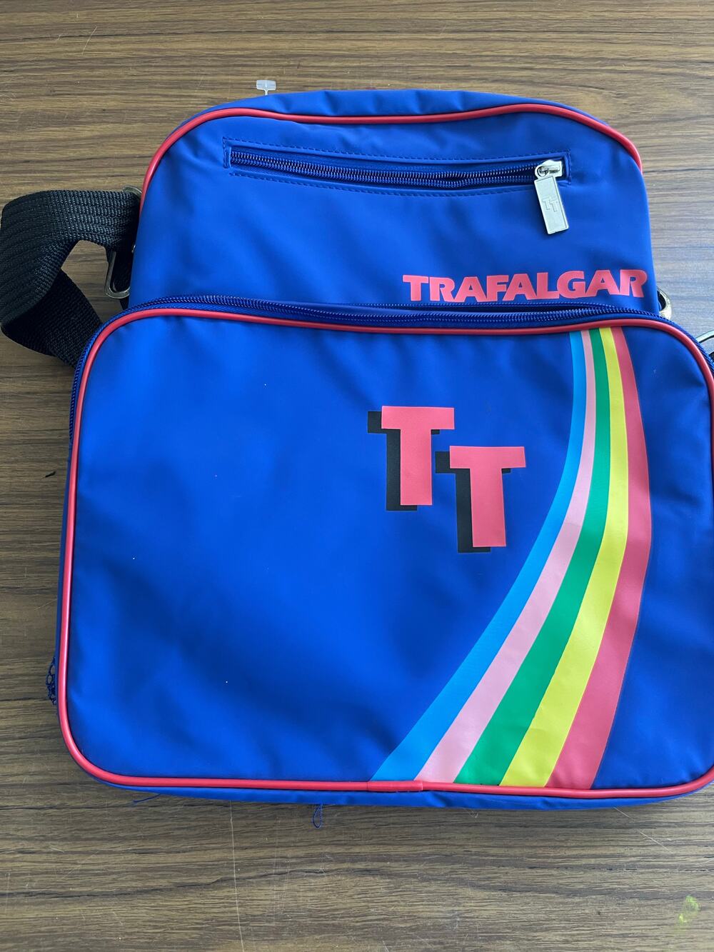 Trafalgar blue shoulder bag with rainbow stripe graphic and dual zip compartment